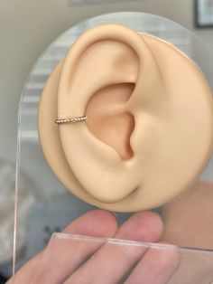 a fake ear with a diamond ring in it's middle being held by someone