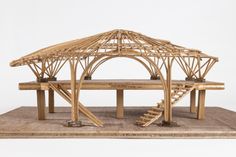 a model of a house made out of bamboo sticks and wood planks with stairs leading up to the roof