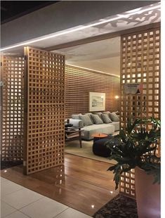 a living room filled with furniture next to a wooden wall covered in latticed screens