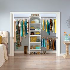 an organized closet with clothes, shoes and purses on the shelves next to a bed