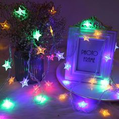 a photo frame with lights around it on a table next to a potted plant