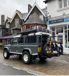 an suv parked in front of a building with a motorcycle on the back