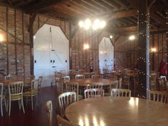 the inside of a restaurant with wooden tables and chairs, exposed brick walls and lights