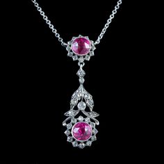 A glamorous antique Edwardian lavaliere necklace from the early 20th Century featuring a beautiful, floral dropper decorated with glistening white pastes and two larger pink pastes that together simulate the beauty of diamonds and pink sapphires.   The silver dropper is suspended from a silver cable chain and held by a ring clasp.  It's in excellent condition and would be perfect for a wedding or special occasion.  WEIGHT: 9 grams MEASURES: Dropper Width 15mm x Height 50mm x Depth 7mm - Chain me Vintage Diamond Gemstone Necklace, Vintage Diamond Necklace With Gemstones, Vintage Oval Necklace With Diamond Accents, Vintage Oval Necklaces With Diamond Accents, Vintage Pink Oval Necklace, Pink Oval Victorian Jewelry, Fine Jewelry Pink Flower Pendant Necklace, Pink Flower Pendant Necklace In Fine Jewelry Style, Pink Flower Pendant Necklace Fine Jewelry