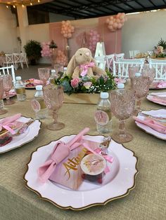 the table is set with pink and gold plates, napkins, cups, and utensils