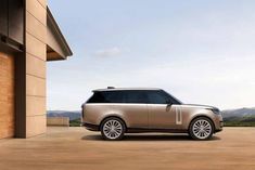 the range rover is parked in front of a building with mountains in the back ground