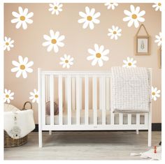 a white crib in front of a pink wall with daisies on the wall