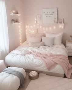 a white bed sitting in a bedroom next to a window with fairy lights on it