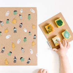 two hands are holding small pieces of paper next to an art project with pumpkins