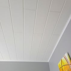 a bedroom with white painted ceilings and a painting on the wall