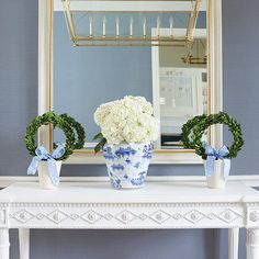 a blue and white vase with flowers sitting on a table in front of a mirror