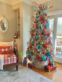 a brightly colored christmas tree in the corner of a room next to a couch and window