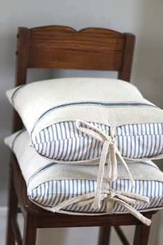 three pillows stacked on top of each other in front of a chair with a wooden back