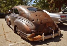 an old rusty car is parked in a parking lot