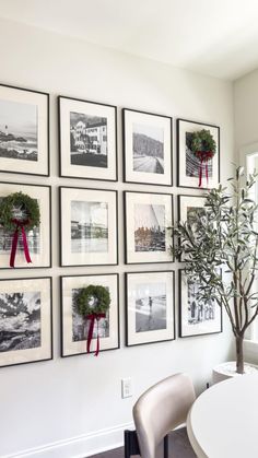 a white dining room table and chairs with pictures on the wall above it that have red ribbons tied around them