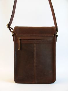 a brown leather shoulder bag sitting on top of a white table