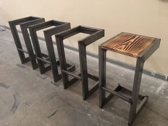 three metal and wood stools sitting next to each other on the floor in front of a wall