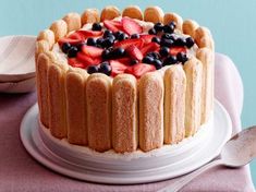 a cake with strawberries and blueberries on top is sitting on a white plate