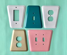 four different types of light switch plates on a green background with one white and one pink