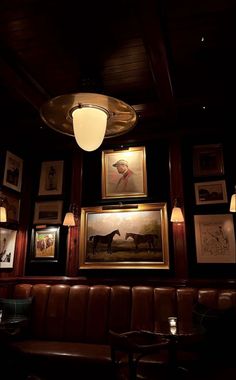 a dimly lit room with framed pictures on the wall and leather booths in front of it