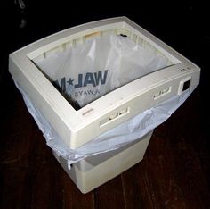 an old computer sitting on top of a wooden floor next to a white plastic bag