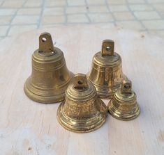 three brass bells sitting on top of a wooden table