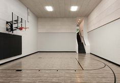 an empty basketball court in a large building with stairs leading up to the second floor