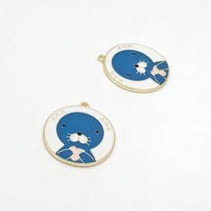 two blue and white cat earrings on a white surface