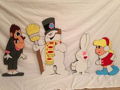 three cartoon characters are standing in front of a white backdrop and one is holding a broom