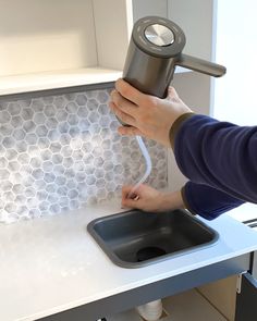 a person using a hair dryer on top of a counter next to a sink