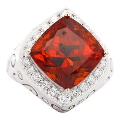 VIntage Spessartine Garnet and Diamond Ring.   This vintage ring features a GIA-certified, vivid cushion-cut spessartine garnet center stone with a carat weight of 12.51. It is paired with 32 round-cut white diamonds totaling 1.11 carats. Crafted in 18K white gold and designed with carved paisley detailing, this ring is comfortably sized at 6.5, but its available for sizing adjustment, and weighs 9.21 grams. A beautiful piece sure to make anyone feel loved, invest in timeless elegance with this garnet cocktail ring.   Item Details: - Type: Vintage Ring  - Metal: 18K White Gold  - Weight: 9.21 grams  - Setting: Prong, Bezel  - Size: 6.5  _______________________  Center Stone Details: - Type: Spessartine Garnet  - Carat: 12.51  - Cut: Cushion  - Color: Orange   GIA Certified  _______________ Formal Cushion Cut Topaz Ring With Gemstone Accents, Gia Certified Cushion Cut Ruby Ring For Formal Occasions, Formal Gia Certified Cushion Cut Ruby Ring, Formal Ruby Ring With Gemstone Accents, Classic Ruby Ring With Gemstone Accents For Formal Occasions, Heirloom Ruby Ring With Gemstone Accents For Formal Occasions, Formal Orange Rings With Halo Setting, Formal Red Gemstones With Accents, Cushion Cut Gemstones For Formal Fine Jewelry