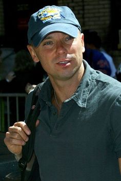 a man wearing a hat and holding a black umbrella