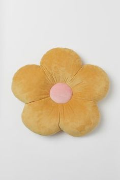 a yellow flower shaped pillow sitting on top of a white wall