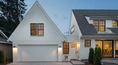 a white house with two garages and lights on the side of it at night