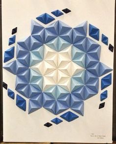 an origami paper art work with blue and white geometric shapes in the center