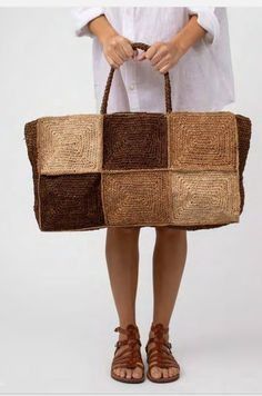 a woman is holding a brown and tan tote bag with squares on the front