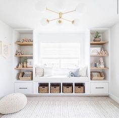 a white room with lots of shelves and baskets on the floor, along with a window seat