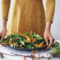 a woman is holding a plate full of vegetables