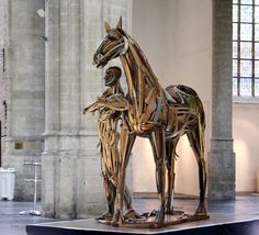 a wooden horse standing on top of a stage in front of a wall with windows