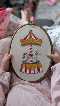 a person holding up a small embroidery piece