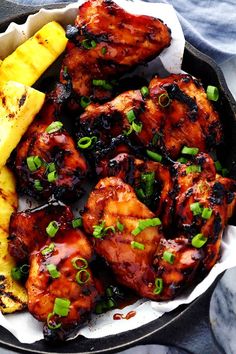 chicken and pineapples in a skillet with some green onions on the side