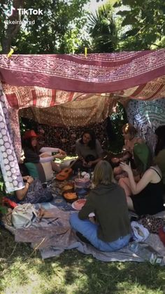 a group of people sitting on top of a blanket under a canopy