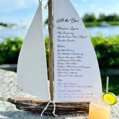 a wooden sailboat with a drink on the table next to it and a sign that says all the best