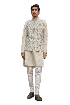 White bundi with zardozi, resham, cutdana embroidery in floral pattern. Paired with textured stripe pattern kurta and churidar. - Aza Fashions Luxury Off White Nehru Jacket With Dabka, Cotton Nehru Jacket With Gota Work For Wedding, Chanderi Nehru Jacket For Reception And Festivals, White Nehru Jacket With Dabka Embroidery, Fitted Nehru Jacket With Dori Work For Navratri, Festive Cotton Nehru Jacket With Gota Work, Fitted Nehru Jacket With Gota Work For Navratri, Fitted Cotton Nehru Jacket With Gota Work, Off White Nehru Jacket With Resham Embroidery