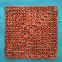 an orange crocheted square on a blue surface