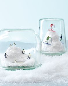 two snow globes with miniature skiers in them sitting on top of the snow