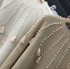 three sweaters with pearls and tassels on them