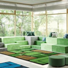 a living room filled with lots of green couches and rugs on the floor