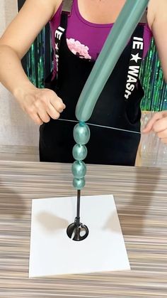 a woman is making a sculpture out of glass beads and plastic pipes with a green handle