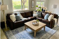 a living room filled with furniture and a blue rug on the floor in front of a window